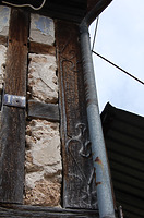 Der aufwändig verzierte Eckständer an der Südwestecke mit einer Reliefschnitzerei lehnt sich an verschliffene Rokokkoformen an. / Scheune in 71549 Auenwald, Däfern (04.08.2010)